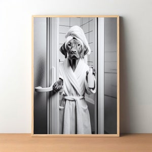 May include: A black and white photo of a dog wearing a white bathrobe and a towel on its head. The dog is holding a bottle of shampoo in its paw and is standing in a bathroom.