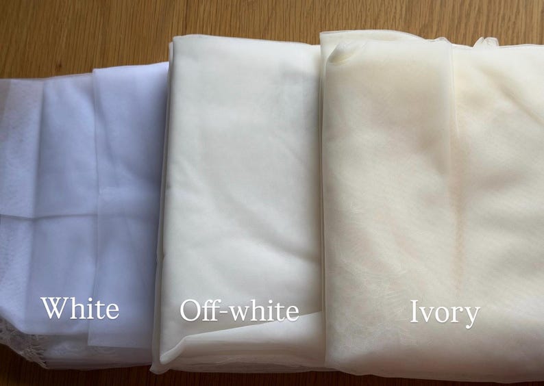 May include: Three folded fabrics in white, off-white, and ivory. The fabrics are labeled with their respective colours. The image shows the different shades of white, suitable for bridal or craft projects.