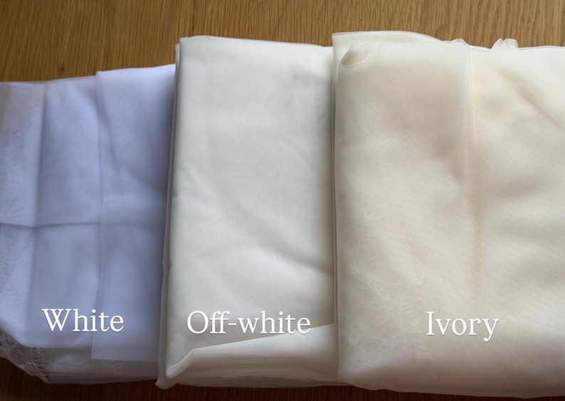 Puede incluir: Tres telas plegadas en blanco, blanco roto y marfil. Las telas est&aacute;n etiquetadas con sus respectivos colores. La imagen est&aacute; bien iluminada, mostrando las texturas y tonos de los materiales. Ideal para proyectos nupciales o de manualidades.
