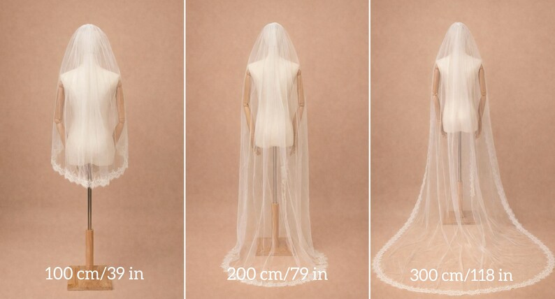 May include: Three white wedding veils displayed on mannequins in varying lengths of 100 cm (39 in), 200 cm (79 in), and 300 cm (118 in). Each sheer veil features a delicate scalloped lace trim along the edges and drapes down the back.