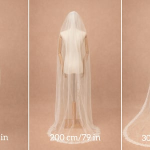 Puede incluir: Tres velos de novia de diferentes longitudes se muestran en maniqu&iacute;es. El velo m&aacute;s corto mide 100 cm, el mediano 200 cm y el m&aacute;s largo 300 cm. Cada velo blanco presenta un delicado ribete de encaje.