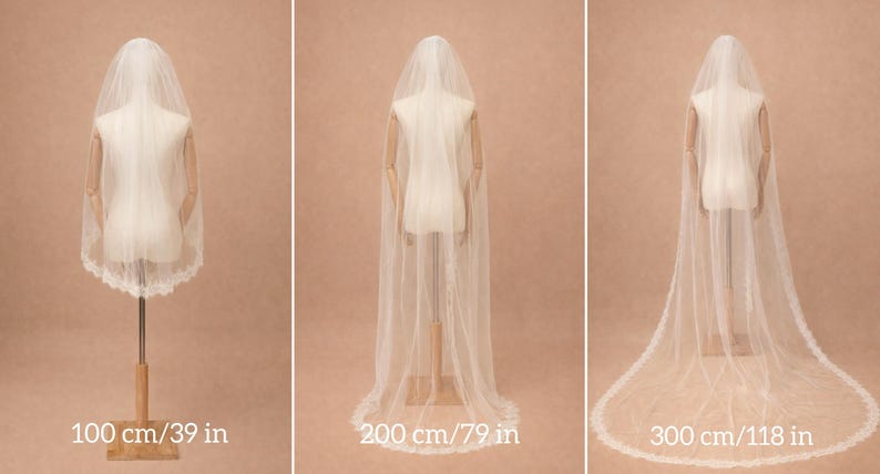 Puede incluir: Tres velos de novia de diferentes longitudes se muestran en maniqu&iacute;es. El velo m&aacute;s corto mide 100 cm, el mediano 200 cm y el m&aacute;s largo 300 cm. Cada velo blanco presenta un delicado ribete de encaje.