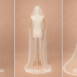 May include: Three bridal veils of different lengths are shown on mannequins. The shortest veil is 100 cm long, the medium veil is 200 cm, and the longest is 300 cm. Each veil is white with a delicate lace trim.