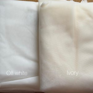 May include: Two fabric samples, one off-white and one ivory, are displayed side by side. The off-white fabric is a bright, clean white, while the ivory fabric has a warmer, creamier tone. The words "Off white" and "ivory" are written on the fabrics.