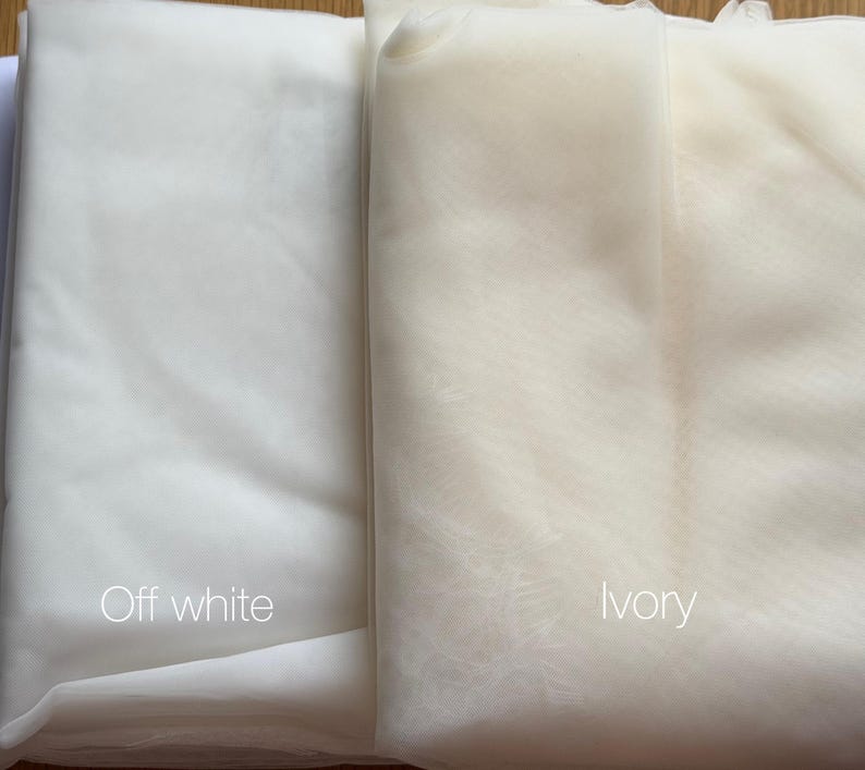 May include: Two fabric samples, one off-white and one ivory, are displayed side by side. The off-white fabric is a bright, clean white, while the ivory fabric has a warmer, creamier tone. The words "Off white" and "ivory" are written on the fabrics.