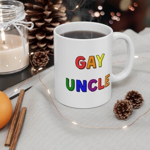 May include: White ceramic coffee mug with a rainbow colored design that says "Gay Uncle".