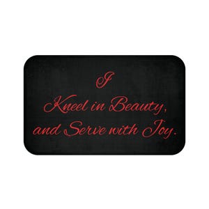 May include: Black doormat with the text "I Kneel in Beauty, and Serve with Joy." in red cursive font.