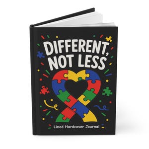 May include: A black hardcover journal with the white text "DIFFERENT, NOT LESS" printed on the front cover. Below the text is a heart-shaped ribbon graphic composed of colorful interlocking puzzle pieces in red, blue, green, and yellow.
