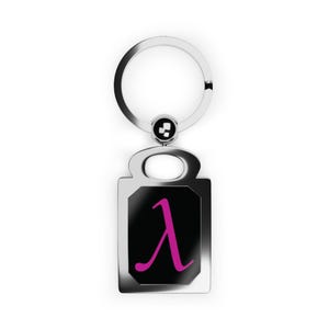 May include: A silver-toned metal keychain featuring a rectangular pendant with a black center inlay. The pendant displays a bright pink Greek letter lambda symbol. The keychain includes a circular split ring for keys and a small circular connector.
