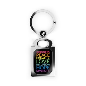 May include: A silver keychain with a black rectangular tag. The tag has the words "KINDNESS, PEACE, EQUALITY, LOVE, INCLUSION, HOPE, DIVERSITY" written in rainbow colors.