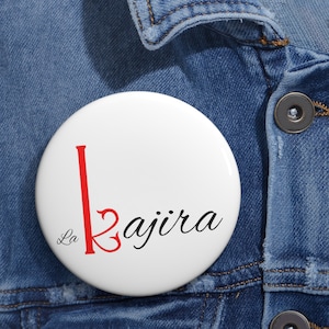 May include: White button with a red "L" and the text "La Kajira" in black cursive script.