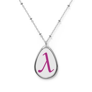 Könnte beinhalten: Eine silberfarbene Halskette mit einem tropfenförmigen Anhänger, der einen weißen Hintergrund und ein mittig platziertes, magentafarbenes griechisches Lambda-Symbol aufweist. Der Anhänger hängt an einer feinen silberfarbenen Kette mit kleinen Metallperlen.