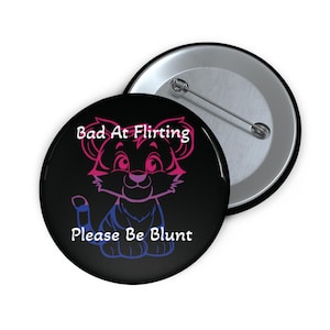 May include: A black button with a pink and blue tiger cub illustration. The text "Bad At Flirting Please Be Blunt" is written in white on the button.