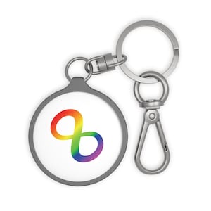 May include: A round, gray keychain with a white center featuring a rainbow-colored infinity symbol. The keychain has a silver clasp and a key ring. The infinity symbol transitions from red to purple.
