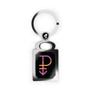 May include: A silver-colored metal keychain with a rectangular pendant. The pendant features a black background with a pink and orange symbol. The keychain has a circular key ring.