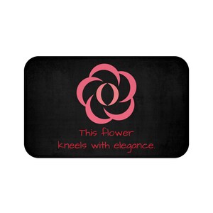 以下が含まれることがあります： ピンクのスタイリッシュな花柄と「This flower kneels with elegance.」というテキストが書かれた黒い玄関マット