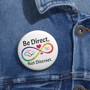 May include: A white button with a rainbow infinity symbol and the text "Be Direct, Not Discreet."