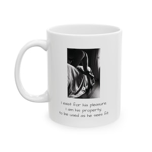 Może przedstawiać: Biały ceramiczny kubek z czarno-białym zdjęciem osoby w szpilkach na łóżku oraz nadrukowanym tekstem: I exist for his pleasure. I am his property, to be used as he sees fit. Kubek posiada wyprofilowane ucho i gładką powierzchnię o błyszczącym wykończeniu.