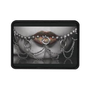 May include: A close-up of a person's lips with a silver chain and ring piercing. The lips are painted a vibrant orange and yellow color.