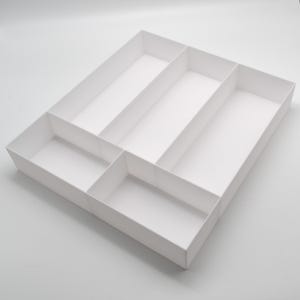 Può includere: Un organizer rettangolare bianco con più scomparti. L'organizer è diviso in diverse sezioni di varie dimensioni, creando una soluzione di archiviazione. I compartimenti sono progettati per contenere e separare gli oggetti. Il design generale è pulito e minimalista.