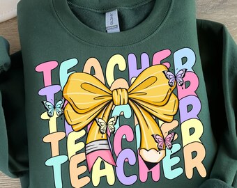 May include: A dark green sweatshirt with a colorful graphic design that says "Teacher" with a yellow bow and butterflies.