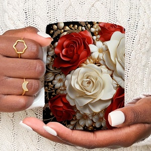 May include: White ceramic coffee mug with a black background and a floral design featuring red, white, and gold roses.