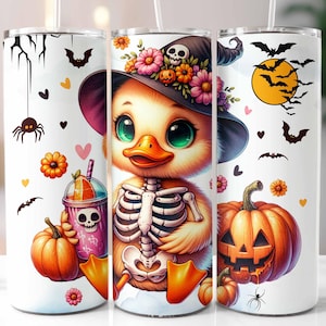 May include: A white tumbler with a Halloween-themed design featuring a cartoon duck wearing a witch hat and holding a pumpkin. The duck has a skeleton design and is holding a glass of orange juice. The tumbler has a black and white spider, bats, and hearts around the design.