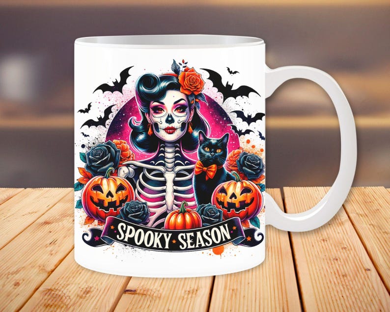 May include: White ceramic mug with a colorful illustration of a skeleton woman with a black cat, pumpkins, and bats. The text "Spooky Season" is printed on the mug.