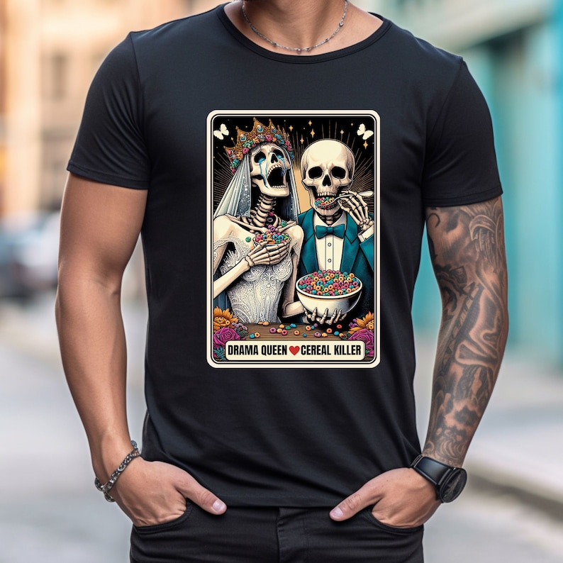 May include: A black t-shirt with a graphic of two skeletons dressed as a bride and groom eating cereal. The text "Drama Queen Cereal Killer" is below the skeletons.