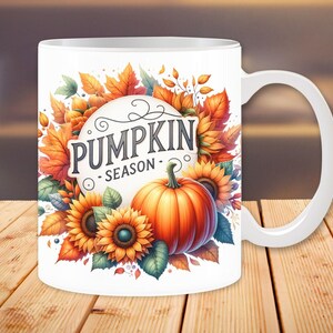 Pu&ograve; includere: Tazza in ceramica bianca con un design autunnale. La tazza presenta una zucca, girasoli e foglie in tonalit&agrave; di arancione, giallo e marrone. Il testo "Pumpkin Season" &egrave; scritto in un font decorativo.
