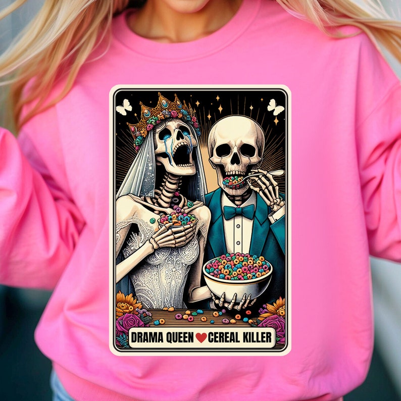May include: A colorful illustration of two skeletons dressed as a bride and groom. The bride is crying and holding a bowl of cereal. The groom is eating cereal with a spoon. The text below the image reads "Drama Queen &hearts; Cereal Killer".
