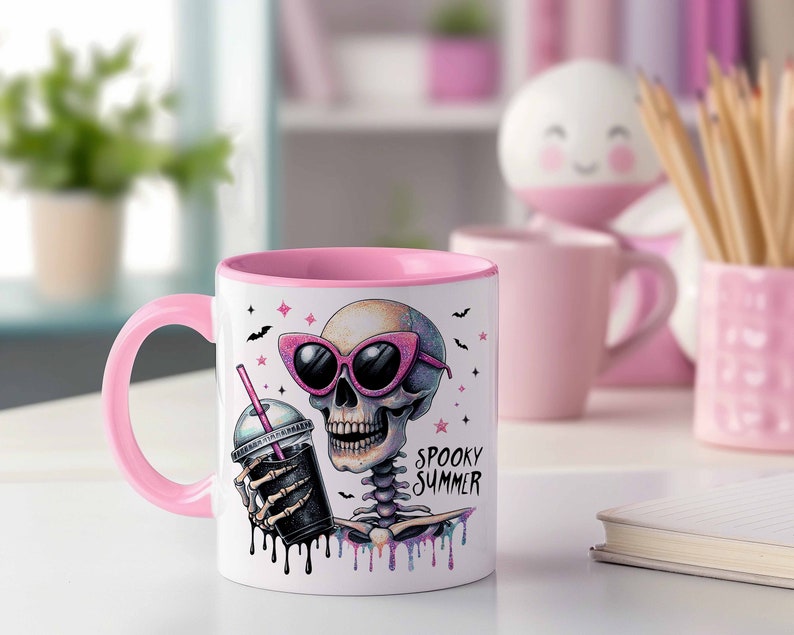 May include: Pink and white ceramic mug with a skeleton wearing sunglasses and holding a pink and black iced drink. The mug has the text "Spooky Summer" on it.