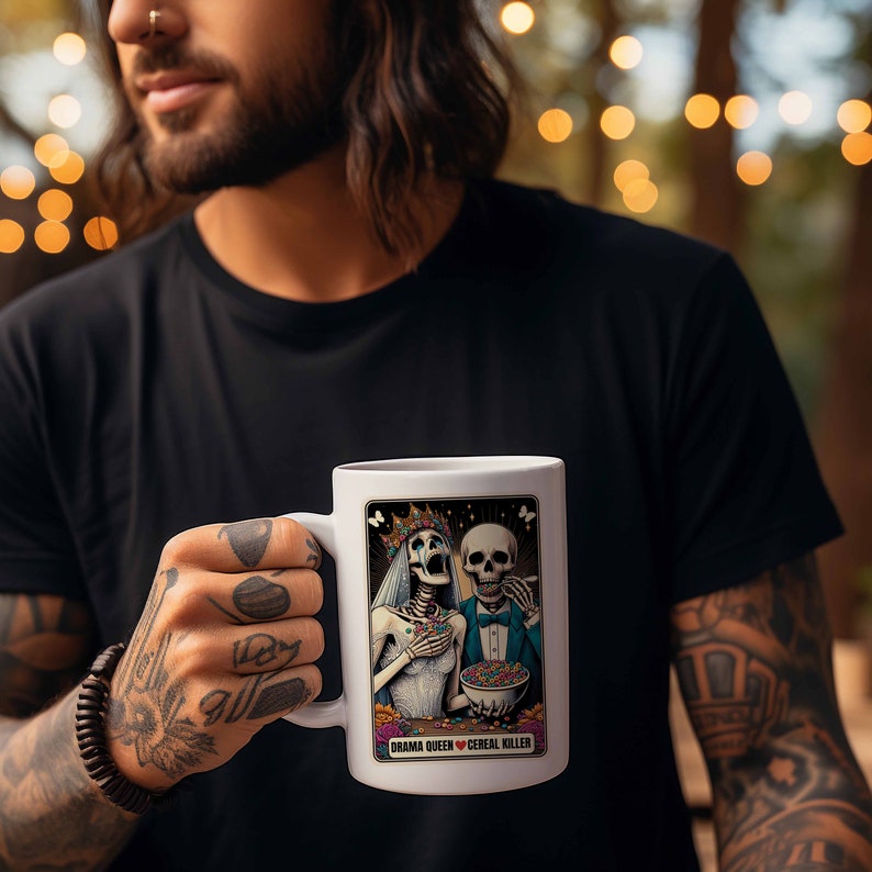 May include: White ceramic mug with a colorful illustration of two skeletons holding bowls of cereal. The text "Drama Queen Cereal Killer" is printed below the image.