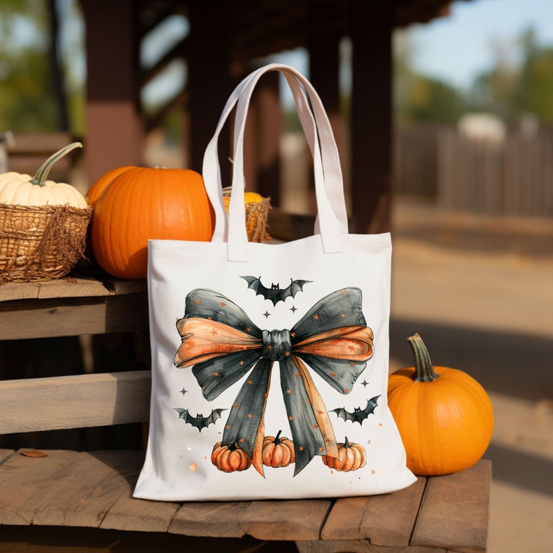 May include: White tote bag with a black and orange bow, bats, and pumpkins. The bag has a black and orange bow with a gray and white polka dot pattern. There are bats and pumpkins on the bag.