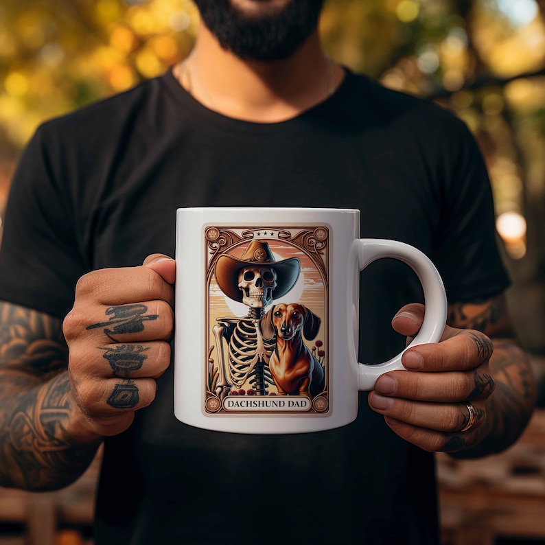 Op de afbeelding: Witte keramische mok met een kleurrijke illustratie van een skelet dat een cowboyhoed draagt en een teckel vasthoudt. De tekst "Dachshund Dad" is onder de afbeelding gedrukt.