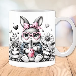 Może przedstawiać: Biały kubek ceramiczny z czarno-białym rysunkiem kr&oacute;lika w r&oacute;żowych okularach w kształcie serca, r&oacute;żowej kokardce w białe kropki i dżinsowej kurtce. Kr&oacute;lik trzyma r&oacute;żowy nap&oacute;j ze słomką. Kubek ma czarno-białe paski jajko i biały kwiat po obu stronach kr&oacute;lika.