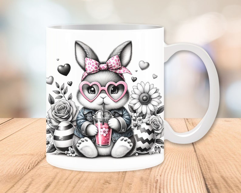 Może przedstawiać: Biały kubek ceramiczny z czarno-białym rysunkiem kr&oacute;lika w r&oacute;żowych okularach w kształcie serca, r&oacute;żowej kokardce w białe kropki i dżinsowej kurtce. Kr&oacute;lik trzyma r&oacute;żowy nap&oacute;j ze słomką. Kubek ma czarno-białe paski jajko i biały kwiat po obu stronach kr&oacute;lika.