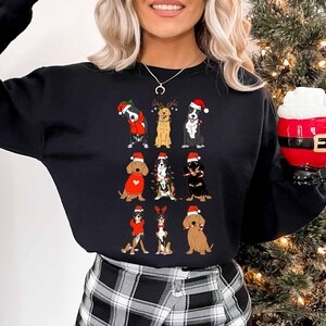 May include: Black sweatshirt featuring a festive design of various dog breeds wearing Santa hats and holiday attire. The dogs are arranged in rows, adding a touch of holiday cheer. The sweatshirt is a comfortable, casual style.