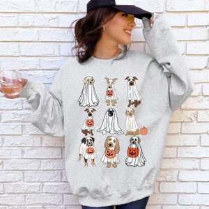 Pu&ograve; includere: Felpa grigio chiaro con un design a tema Halloween. Il design include illustrazioni di varie razze di cani vestiti da fantasmi e con lanterne a forma di zucca. &Egrave; inclusa anche una piccola zucca arancione. La felpa &egrave; uno stile casual e confortevole.