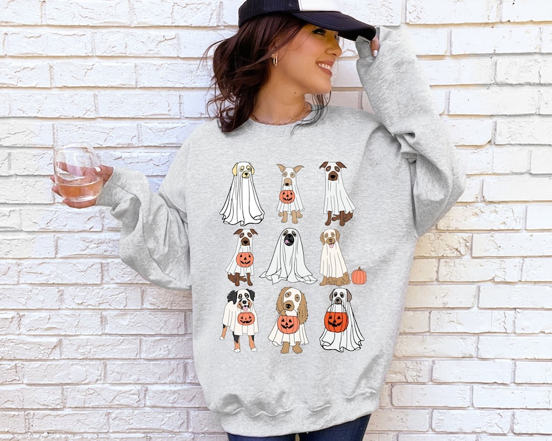 Pu&ograve; includere: Felpa grigio chiaro con un design a tema Halloween. Il design include illustrazioni di varie razze di cani vestiti da fantasmi e con lanterne a forma di zucca. &Egrave; inclusa anche una piccola zucca arancione. La felpa &egrave; uno stile casual e confortevole.