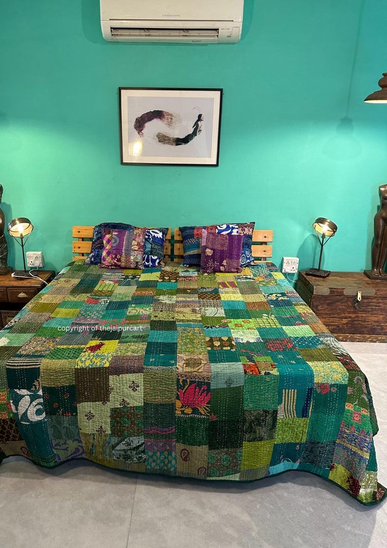 Puede incluir: Una colcha de retazos verde y azul con una variedad de patrones y colores. La colcha est&aacute; en una cama con dos almohadas. La habitaci&oacute;n tiene una pared verde turquesa y un cuadro enmarcado en la pared.