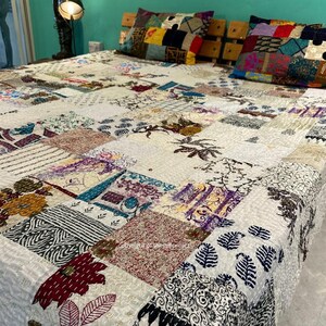 Puede incluir: Una colcha blanca de patchwork con una variedad de patrones y dise&ntilde;os coloridos. La colcha est&aacute; hecha de diferentes telas y est&aacute; acolchada con una puntada corrida. La colcha est&aacute; en una cama con dos almohadas de patchwork coloridas.