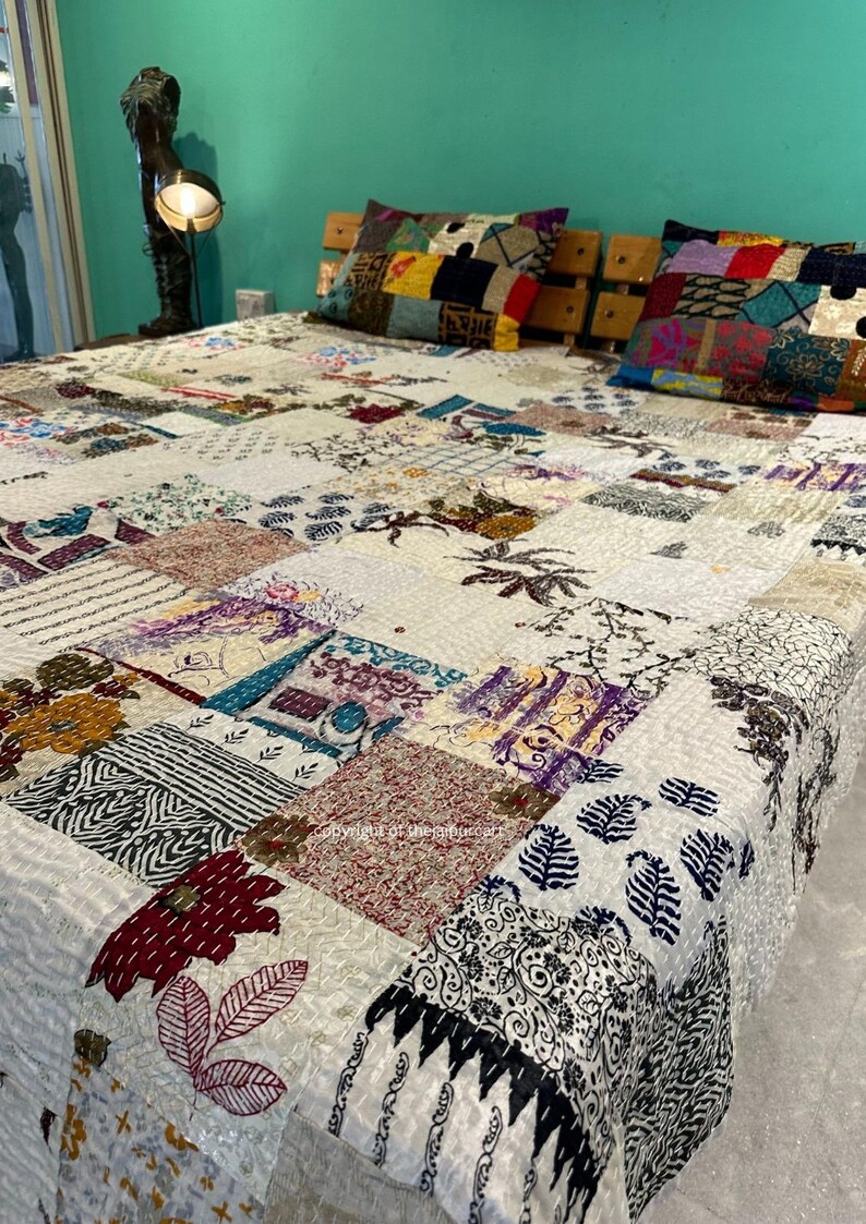 Puede incluir: Una colcha blanca de patchwork con una variedad de patrones y dise&ntilde;os coloridos. La colcha est&aacute; hecha de diferentes telas y est&aacute; acolchada con una puntada corrida. La colcha est&aacute; en una cama con dos almohadas de patchwork coloridas.
