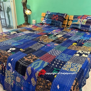 May include: A blue kantha quilt with a patchwork design. The quilt is made of various fabrics with different patterns and colors, including floral, geometric, and paisley. The quilt is hand-stitched and has a unique, rustic look.
