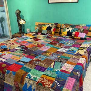 May include: A patchwork quilt and matching pillow set on a bed. The quilt features a vibrant mix of colors and patterns, including red, blue, green, and yellow. The pillows echo the quilt's design. The bed has a wooden headboard.