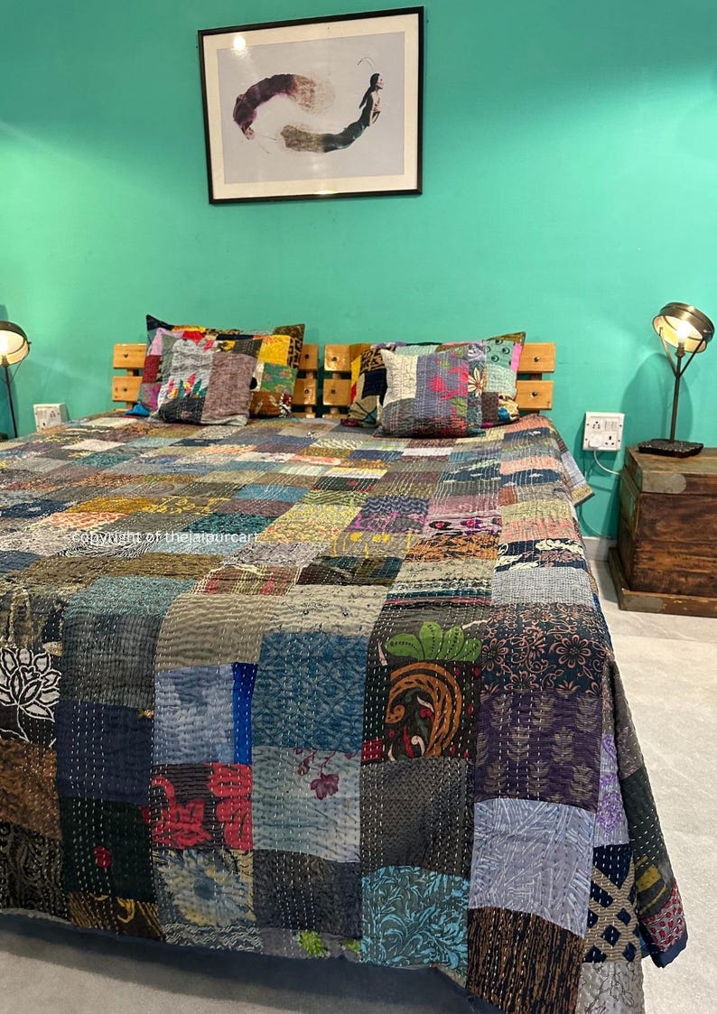 Puede incluir: Una colcha de retazos con una variedad de colores y patrones, incluyendo dise&ntilde;os florales, geom&eacute;tricos y paisley. La colcha est&aacute; hecha de telas recicladas y est&aacute; cosida a mano. Est&aacute; colocada sobre una cama con almohadas y una cabecera de madera.
