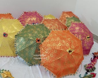 May include: A collection of colorful, decorative umbrellas. The umbrellas feature intricate gold floral patterns on various colored fabrics, including yellow, green, orange, and pink. Each umbrella has a decorative fringe trim and a wooden handle.