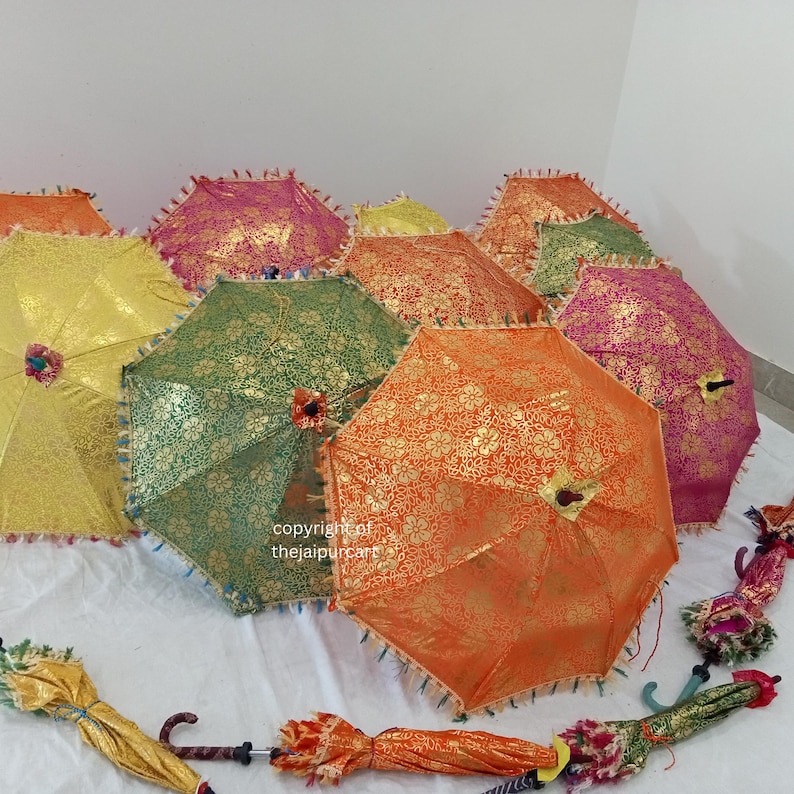 Pode incluir: Um grupo de guarda-chuvas decorativos coloridos com detalhes dourados e guarni&ccedil;&otilde;es de franjas. Os guarda-chuvas s&atilde;o feitos de tecido e t&ecirc;m cabos de madeira.
