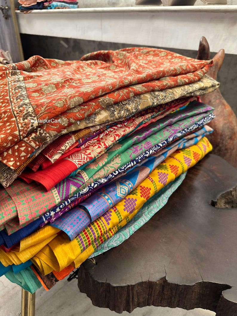 May include: A stack of colorful fabric scarves with various patterns and designs. The scarves are folded and stacked on top of each other, creating a vibrant and textured display. #jaipurCart