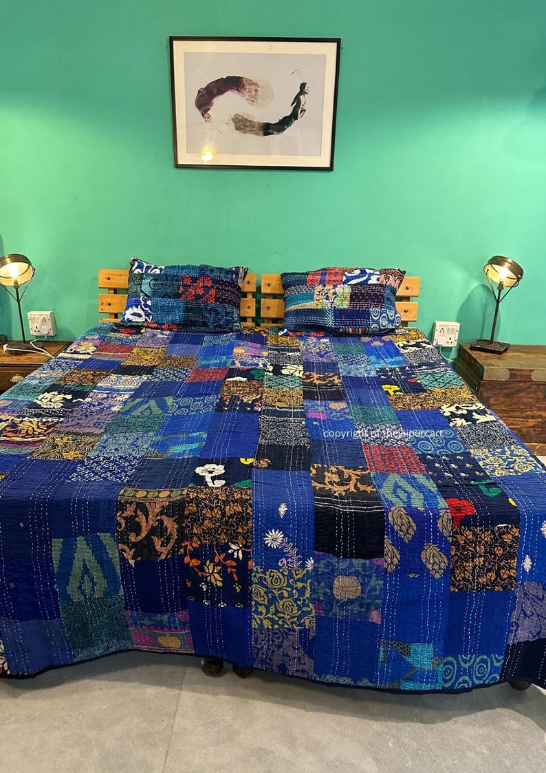 Puede incluir: Un edred&oacute;n azul de patchwork con una variedad de patrones coloridos. El edred&oacute;n est&aacute; colocado sobre una cama con dos fundas de almohada a juego. La cama est&aacute; en una habitaci&oacute;n con paredes de color turquesa y dos l&aacute;mparas sobre mesitas de noche.